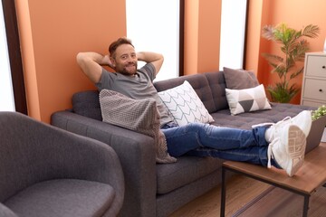 Middle age man relaxed with hands on head sitting on sofa at home