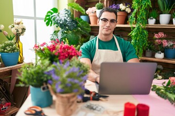 Naklejka na ściany i meble Young hispanic man florist smiling confident using laptop at flower shop
