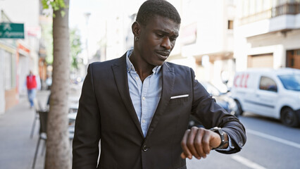 Handsome african man in suit checking time on watch in a city street setting.