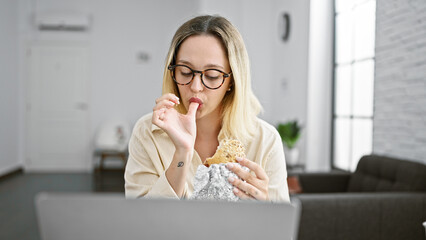 Young blonde woman business worker eating sandwich working at the office