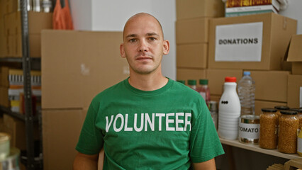 Young hispanic man volunteer sitting on table with serious face at charity center