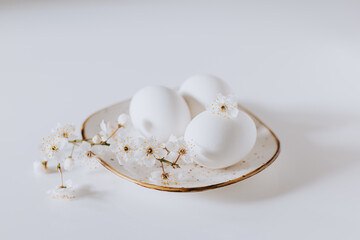 Beautiful branch with white blossom and eggs on a white background. Minimal concept.