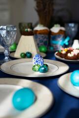 Obraz na płótnie Canvas Holiday table laid for Easter celebration with Easter cakes, cookies in shape of nests, tradition cottage cheese Easter and colorful hand-pained Easter eggs