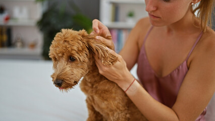 Young caucasian woman with dog sitting on the bed examining at bedroom