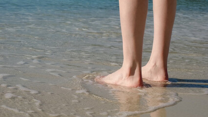 Woman standing on sea sandy shore. Enjoying the ocean. Bare female feet