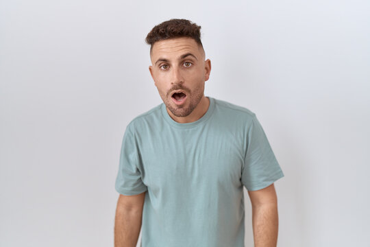Hispanic man with beard standing over white background afraid and shocked with surprise and amazed expression, fear and excited face.