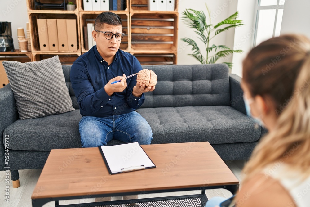 Canvas Prints Young latin man psychologist having mental session holding brain at psychology clinic