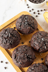Healthy double chocolate chip muffins with bananas on a wooden plate. Eating sweet vegan dessert or snack. Close-up. Top table view.