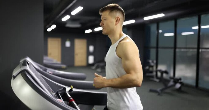 Male athlete running on treadmill in gym 4k movie slow motion. Cardio training concept