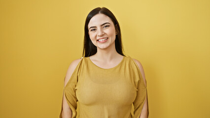 Obraz premium Portrait of a happy, young, hispanic woman wearing a gold shirt against a vibrant yellow background, showcasing beauty and positivity.
