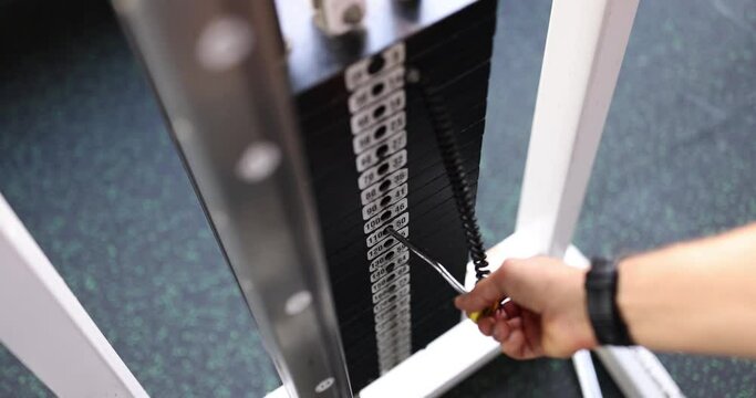 Male hand setting gravity weight on simulator in gym closeup 4k movie slow motion. Strength sport training concept
