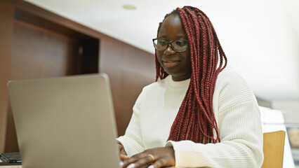 African american woman with braids working on laptop in modern office