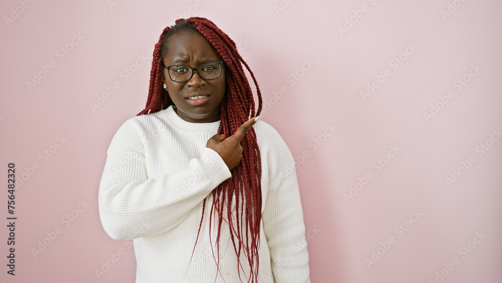 Sticker Adult black woman with braids wearing glasses and a white sweater pointing to the side against a pink background.