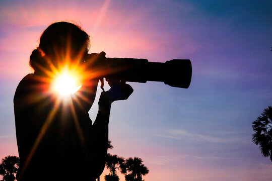 Silhouette of a woman photographer in a palm tree garden at sunrise - Powered by Adobe