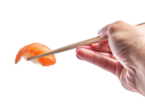  Hand of man holding salmon nigiri with chopsticks over isolated white background