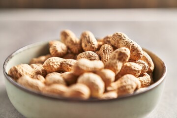A close-up of unshelled peanuts in a ceramic bowl, showcasing a healthy natural snack.