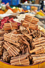 Bundles of cinnamon sticks piled in a market setting, offering a rich aroma and warm flavor.