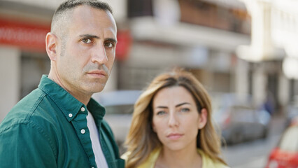 Man and woman couple standing together with serious face at street