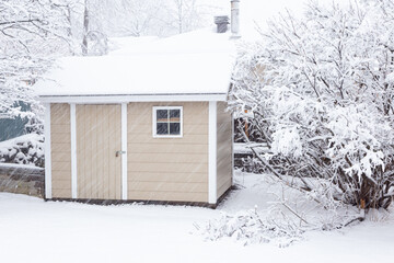 Small beige shed seen in yard during a heavy snowfall in the morning, Quebec City, Quebec, Canada