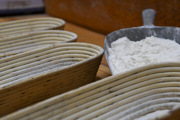 Fototapeta na wymiar Schaufel mit Mehl neben gestapelten Bastkörben in einer Bäckerei
