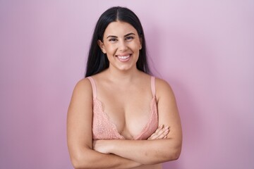 Young hispanic woman wearing pink bra happy face smiling with crossed arms looking at the camera. positive person.