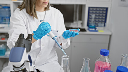 Focused woman in lab conducts experiment with pipette and test tube, in an indoor laboratory...