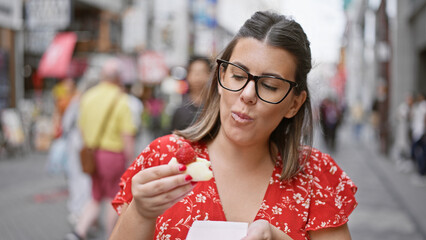 Gorgeous hispanic girl in specs relishing strawberry japanese mochi on osaka's famous dotonbori...