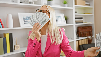 Beautiful blonde business woman kisses dollars, portrait of success at the office