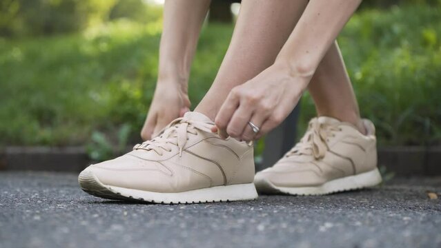 A Caucasian woman ties her shoelaces - closeup