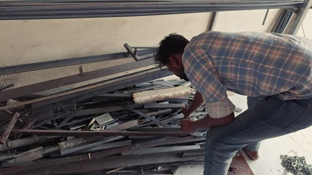 Man organizing metal profiles in a workshop depicting manual labor and organization in an industrial setting men searching iron angles at a fabrication workshop