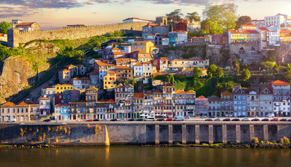 Antique town Porto, Portugal. Sunset sun over silhouettes skyline of porto city roofs houses along...
