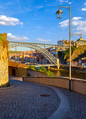 Porto, Portugal. Evening sunset picturesque view form the old town street with antique houses and red roofs lamp near bridge Ponte de Dom Luis on river Douro. Travel destination in Europe