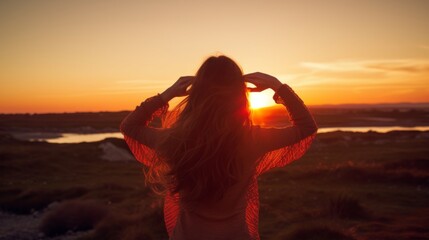 A woman stands on top of a mountain and looks at the sunset. Silhouette of a woman at sunset.