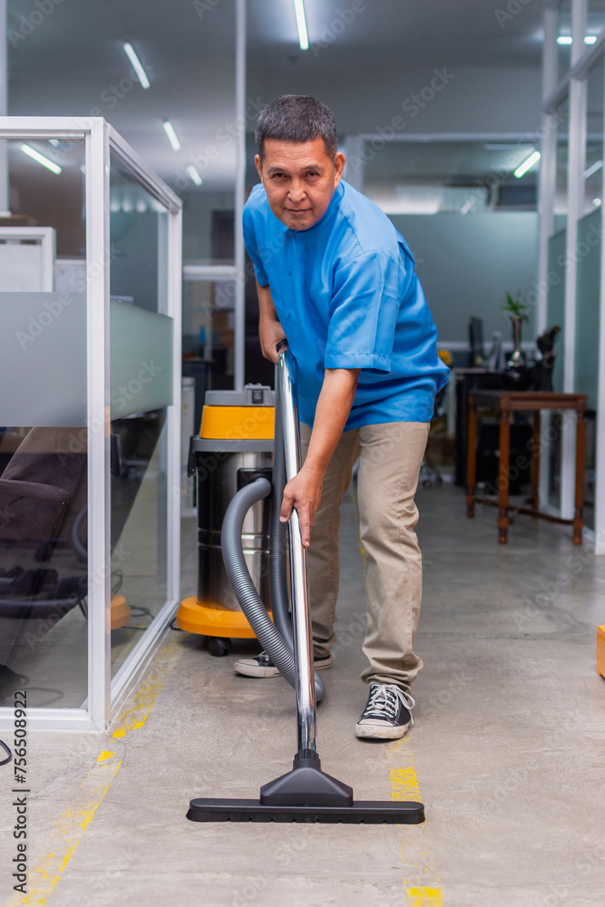 Wall mural a middle aged janitor smiling while cleaning the concrete floor with a professional wet and dry vacu