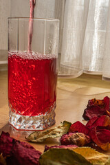 glass of red wine and rose petals