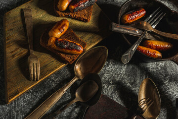 Still life fried sausages in a cast-iron pan on a dark background