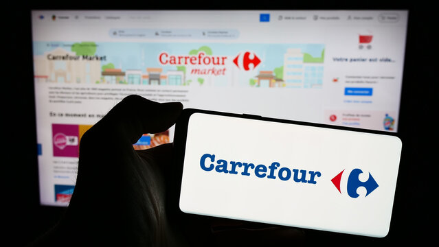 Stuttgart, Germany - 03-01-2024: Person holding smartphone with logo of French retail company Carrefour S.A. in front of website. Focus on phone display.