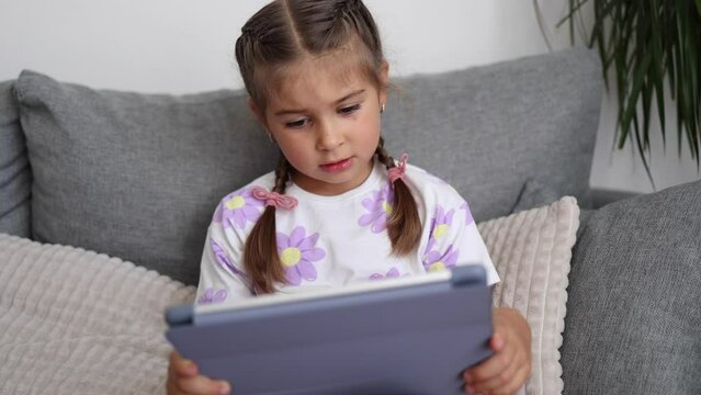 Adorable little girl use tablet at home. Five year old girl play games on tablet