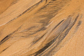 Sand and water texture. Close up photo with the abstract shapes created by a tiny water river over the sands at Atlantic Ocean shore.