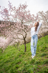 Lovely young woman in a blooming pink and white garden Petrin in Prague, spring time in Europe