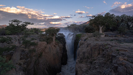 waterfall between baobab trees