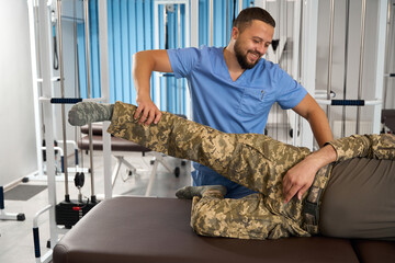Male massage therapist works with a military man at rehabilitation