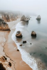 Misty Algarve Beach: A Professional Aerial Shot Capturing Serene Waters and Fog-Enshrouded Rocks in Portugal's Coastal Elegance.