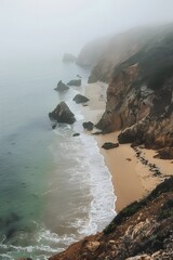 Aerial view of a serene Portuguese beach with fog, showcasing rocks, brown sand, and lush greenery, captured in the vivid Unsplash photography style.