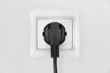 Power electric sockets on a white wall. electric cord plugged into a white electricity rosette on...