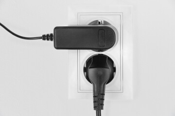 Power electric sockets on a white wall. electric cord plugged into a white electricity rosette on white background. outlet on the white wall