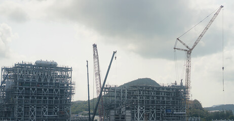 construction site with a tall building in the background. Several workers are on site, and a crane...