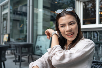 Caucasian or white woman using smart watch to communicate via talk and listen in the coffee shop after work. Beautiful white businesswoman working the city Bangkok, Thailand. 5G wireless technology.