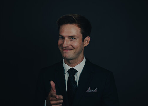 Close-up portrait of a smiling businessman in a suit pointing