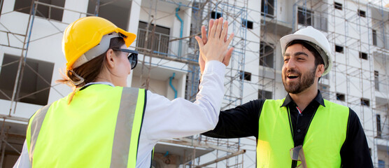Happy team of architect or engineer with success and glad while hi five together at construction...